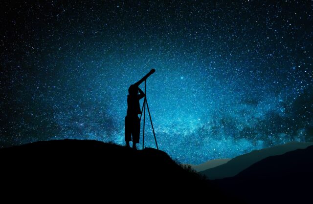 Silhouette of little child looking through a telescope